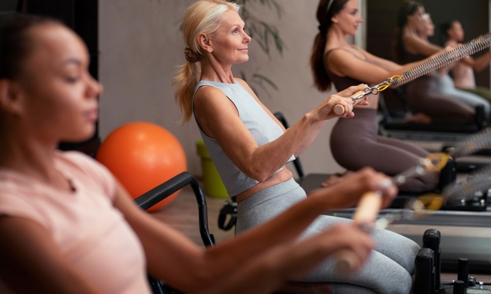 Grupo de mulheres idosas praticando em aula, destacando os benefícios do pilates, principalmente, para a saúde e o bem-estar na terceira idade.