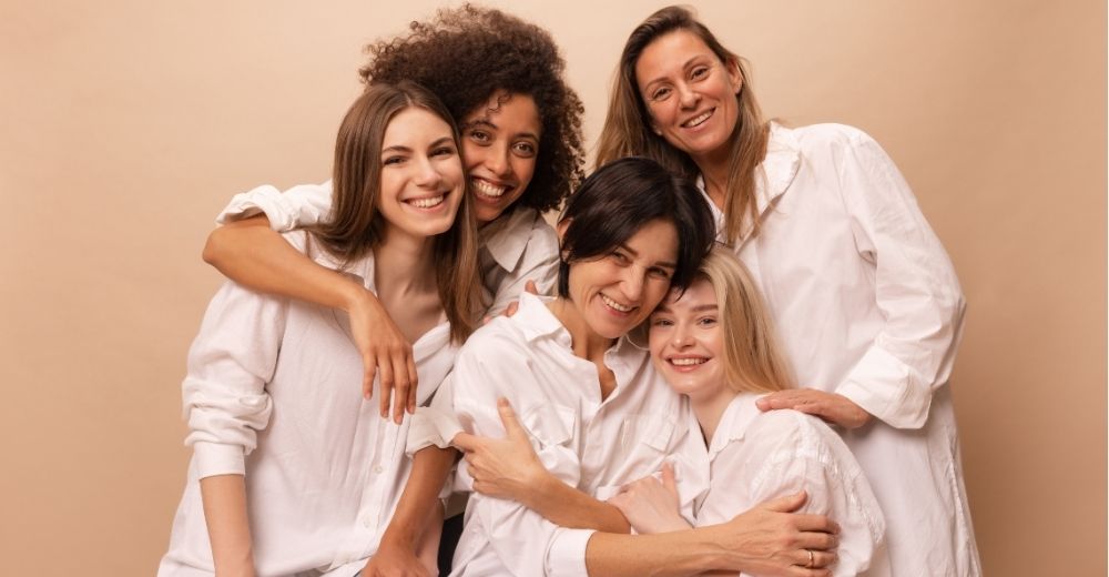 Mulheres de diferentes idades sorrindo e celebrando o Mês da Mulher juntas, simbolizando união, força e diversidade feminina.