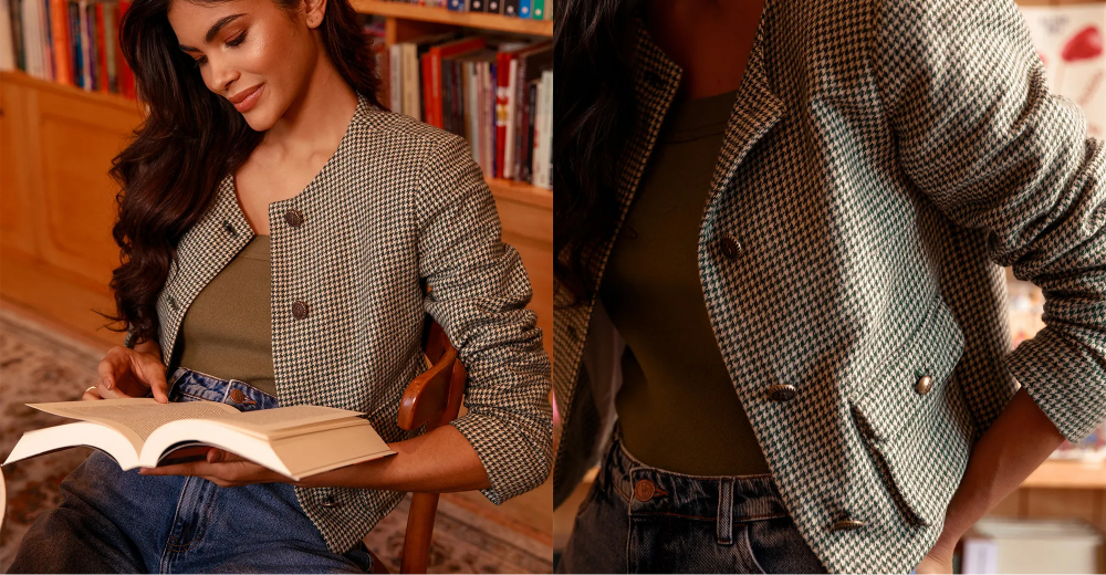 Mulher com casaqueto e jeans em ambiente aconchegante, segurando um livro aberto e posando sentada em uma cadeira. Close mostra o casaqueto xadrez e a cintura com jeans.