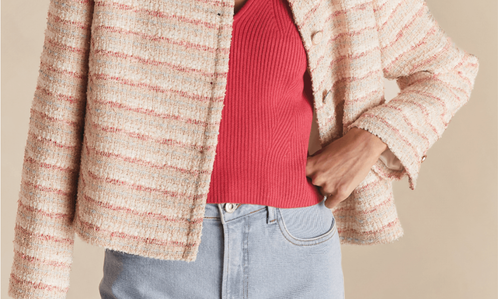 Casaqueto e jeans: pessoa vestindo um casaqueto de tecido claro com textura tweed sobre uma blusa vermelha, combinada com jeans azul claro.